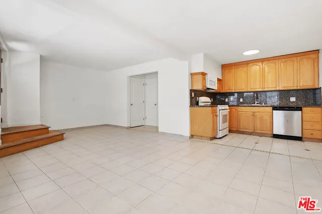 a kitchen with stainless steel appliances granite countertop a stove a sink and white cabinets