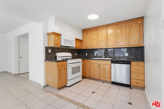a kitchen with granite countertop white cabinets and white appliances