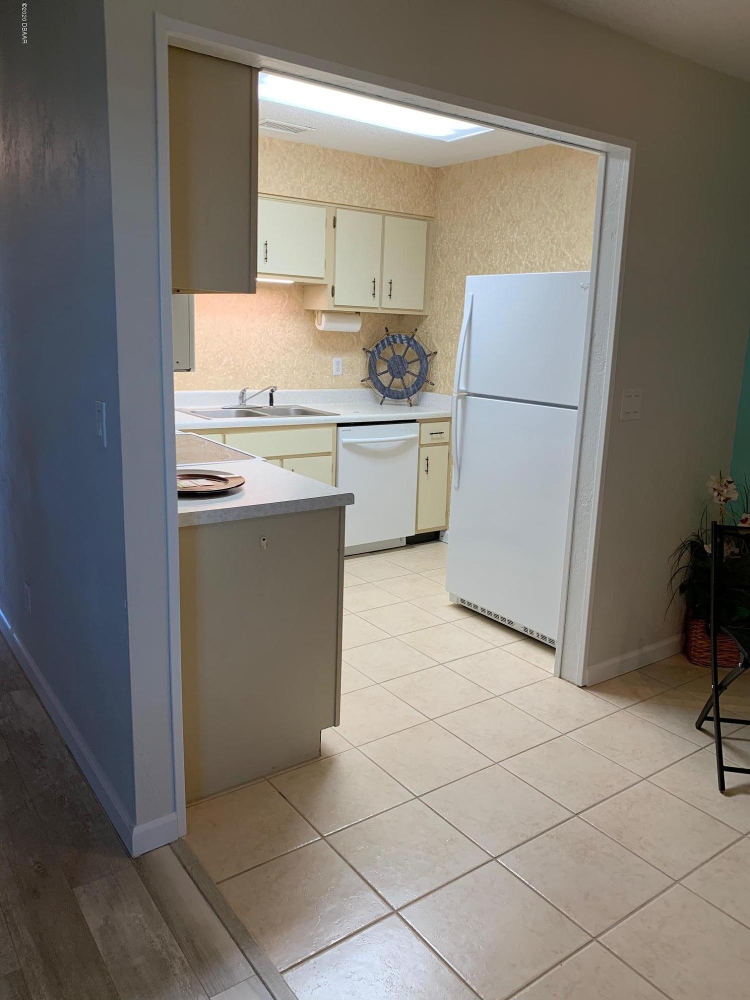 2250 Ocean Shore Boulevard, Unit 2030 Ormond Beach, FL 32176 - Photo 3 of 7 a kitchen with a sink a refrigerator and cabinets
