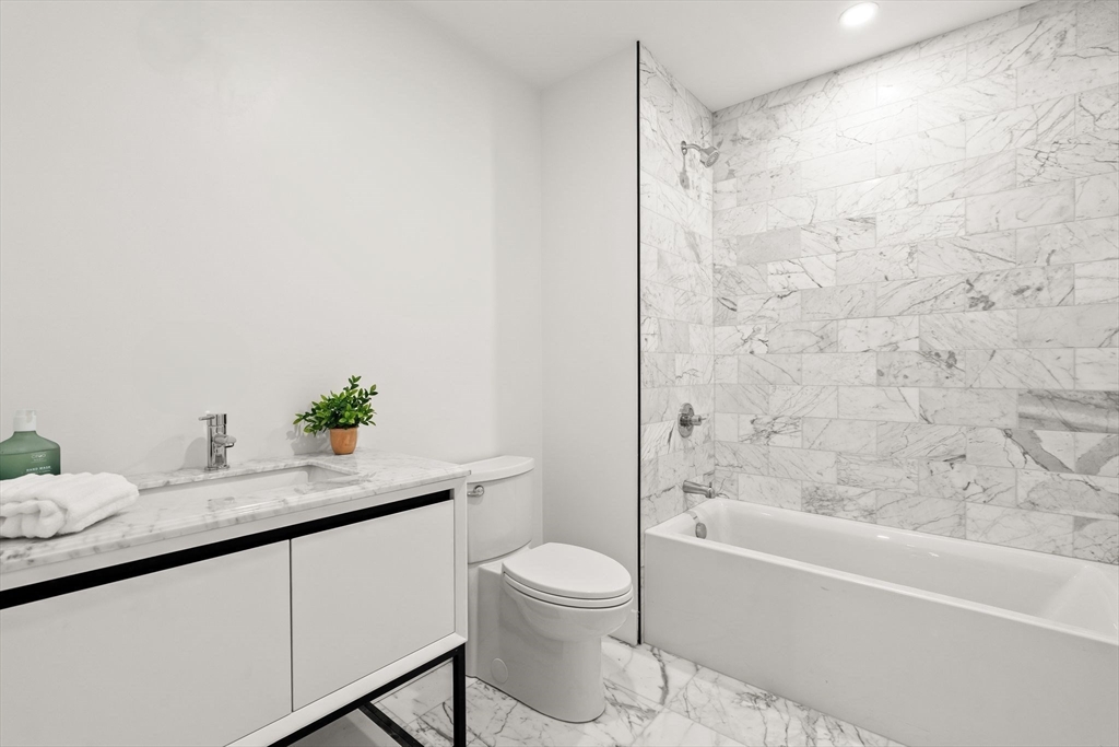 47 Condor Street, Unit 203A Boston, MA 02128 - Photo 11 of 15 a bathroom with a granite countertop sink toilet a bathtub and a shower