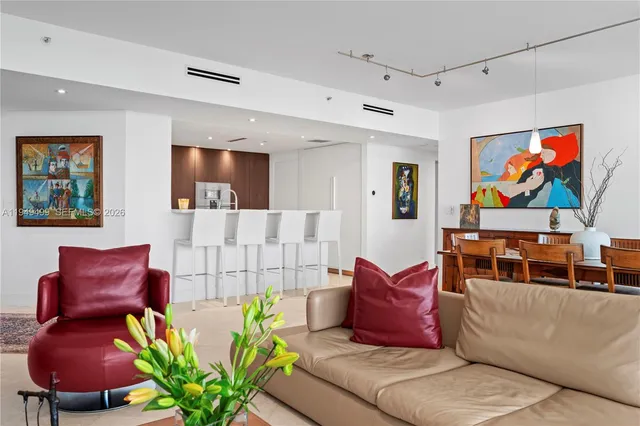 a living room with furniture kitchen view and a large window