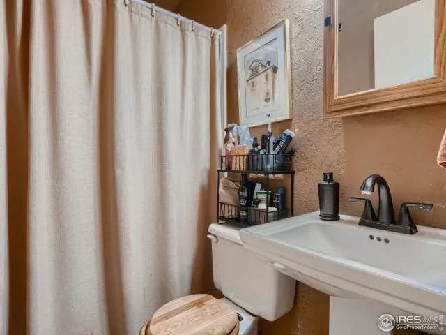 a bathroom with a sink a toilet and shower curtain