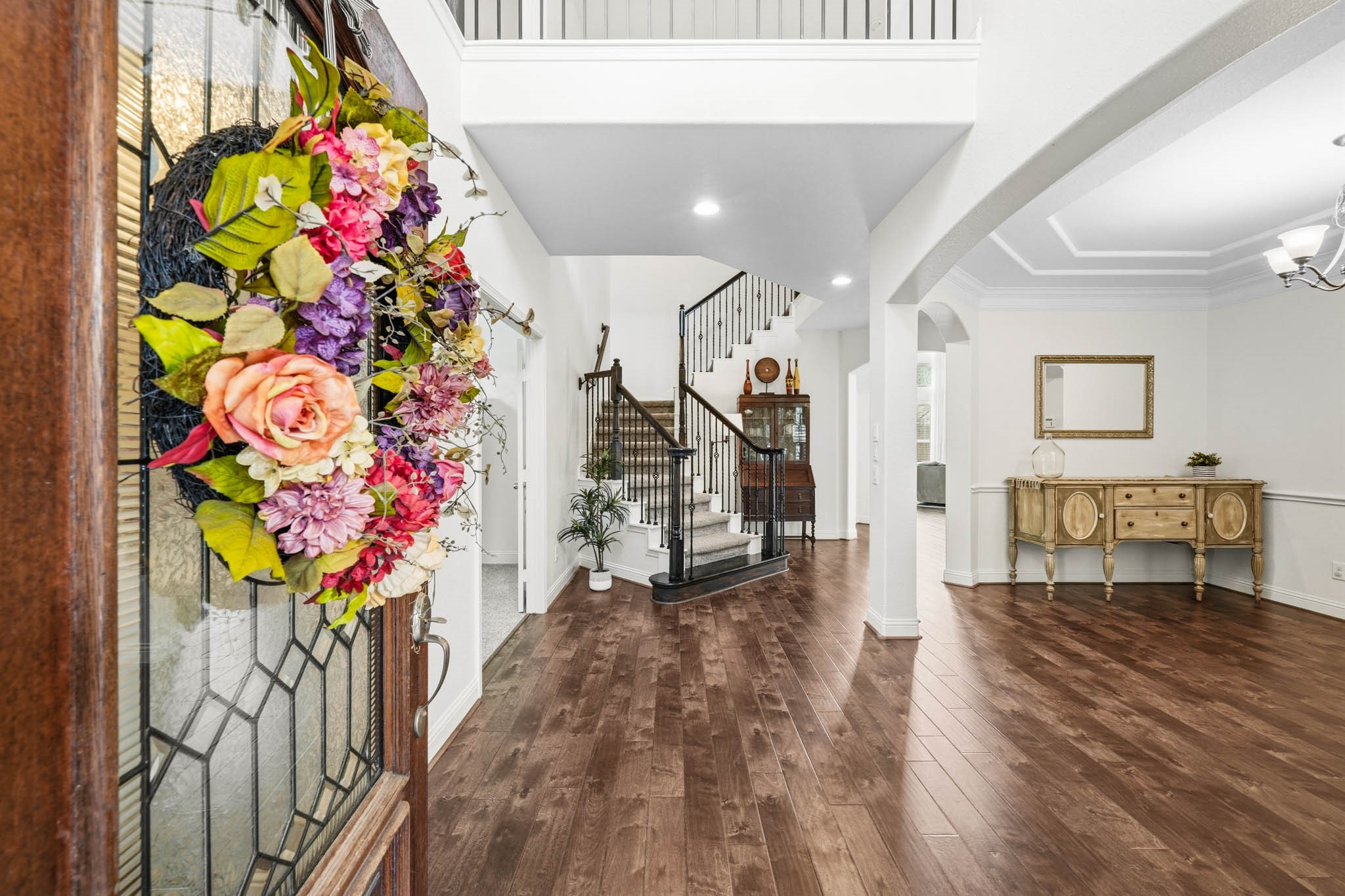 17610 Strackfield Lane Tomball, TX 77377 - Photo 4 of 50 A grand two-story foyer with rich hardwood floors creates a striking first impression, seamlessly connecting to the dining room through an elegant arched opening.