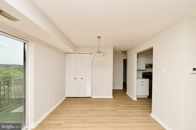a view of an empty room with window and wooden floor