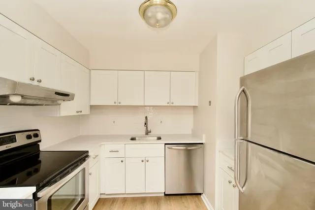 a kitchen with stainless steel appliances white cabinets and a refrigerator