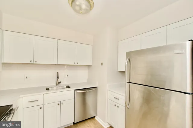 a kitchen with white cabinets and refrigerator
