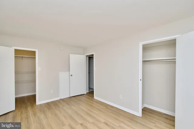 a view of an empty room with wooden floor & closet