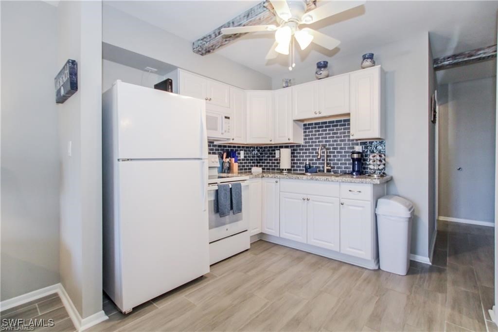 3226 Stringfellow Road St. James City, FL 33956 - Photo 11 of 28 a kitchen with white cabinets and white appliances