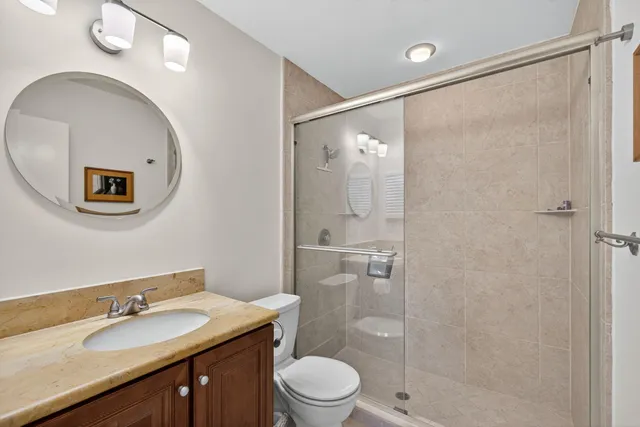a bathroom with a granite countertop sink toilet a mirror and shower