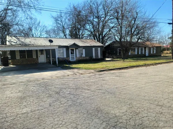 a view of a house with a yard and large trees