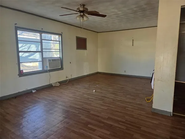 an empty room with wooden floor fan and windows