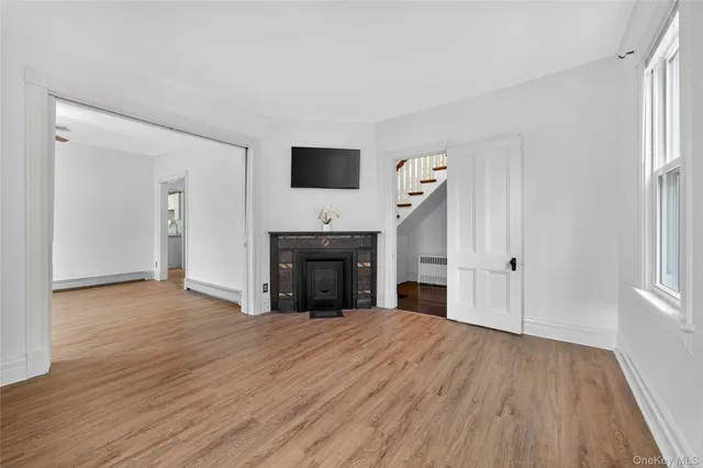 a view of empty room with wooden floor and fireplace
