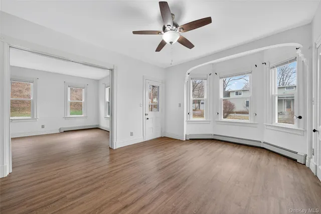 a view of an empty room with window and wooden floor