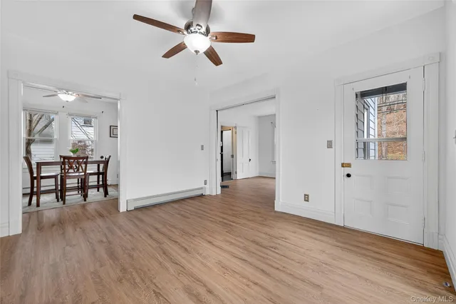 an empty room with wooden floor chandelier fan and windows