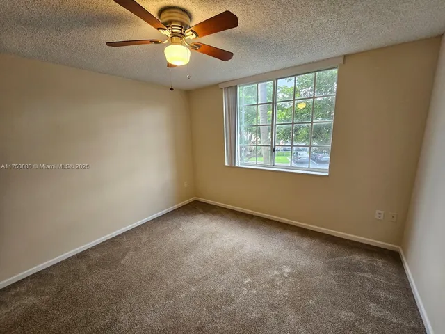 an empty room with a window and a fan