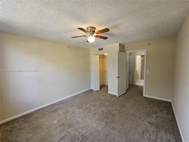 an empty room with closet and a ceiling fan