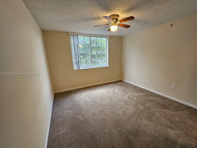 an empty room with windows and chandelier fan