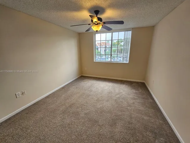 an empty room with a window and a ceiling fan