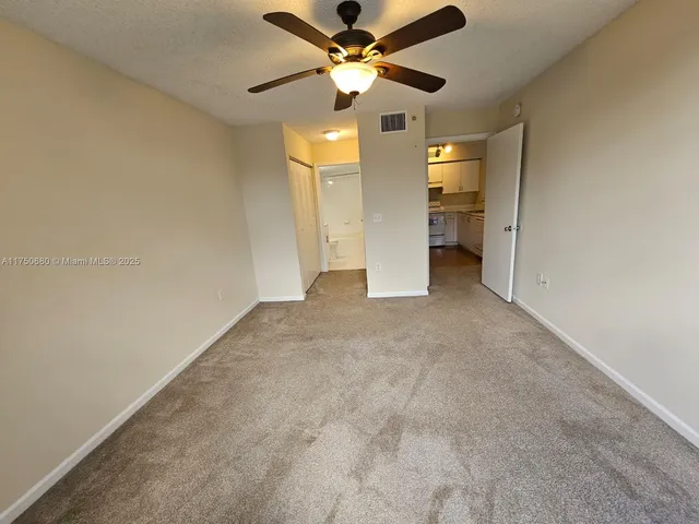 a view of an empty room and kitchen view
