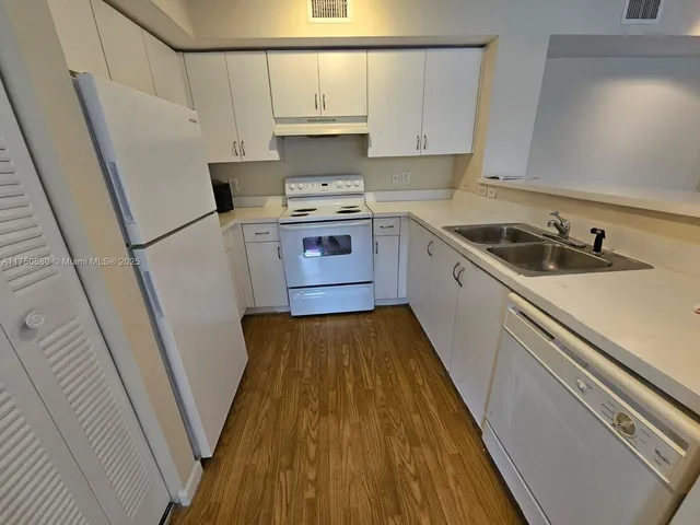 a kitchen with a sink a stove wooden floor and cabinets