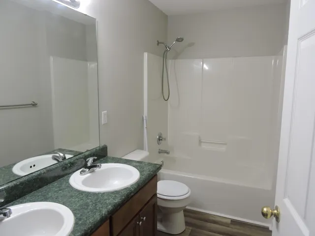 a bathroom with a granite countertop sink toilet a mirror and shower