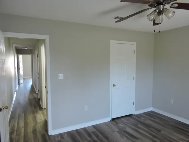 a view of a hallway with wooden floor and a chandelier fan