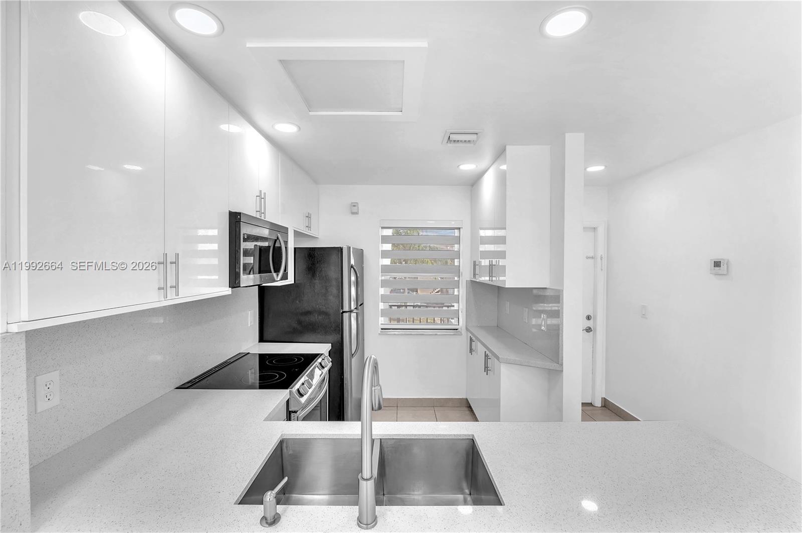7668 Southwest 152nd Avenue, Unit 2211 Miami, FL 33193 - Photo 9 of 20 a kitchen with stainless steel appliances kitchen island granite countertop a refrigerator a sink a stove and white cabinets with wooden floor