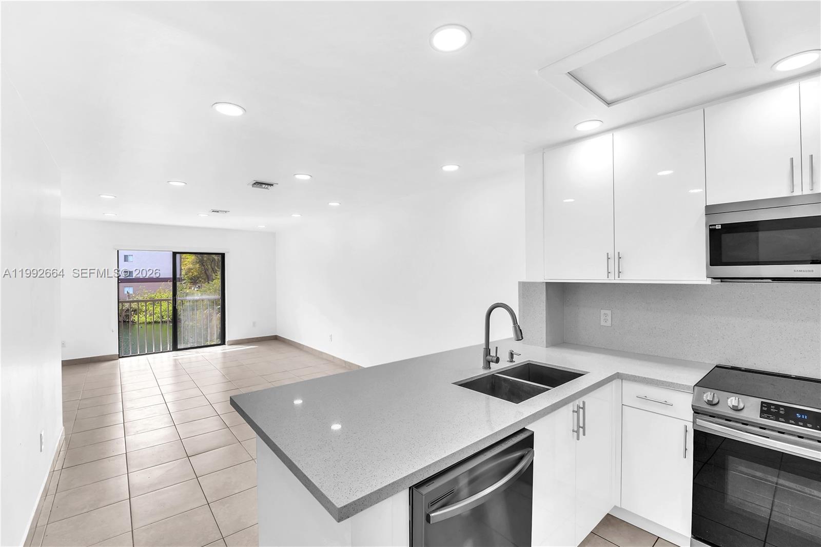 7668 Southwest 152nd Avenue, Unit 2211 Miami, FL 33193 - Photo 10 of 20 a kitchen with stainless steel appliances a sink a stove a microwave a counter top space and cabinets