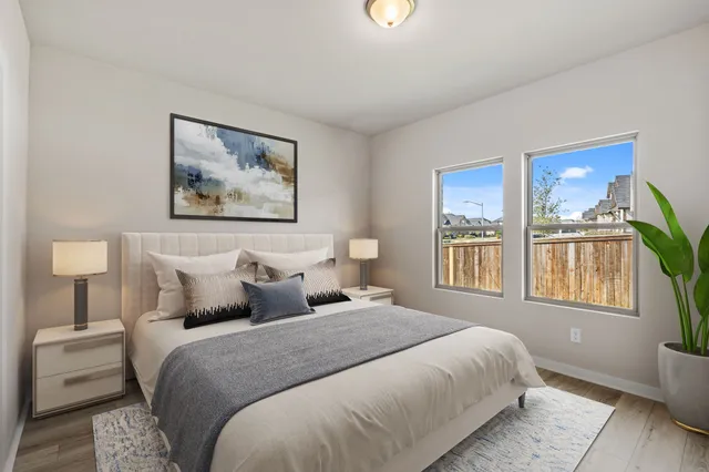 a bedroom with a bed painting on wall and a large window