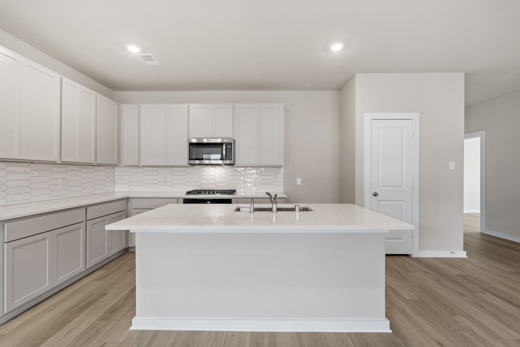 12015 Moonlight Path Drive Conroe, TX 77304 - Photo 3 of 31 a kitchen with stainless steel appliances granite countertop a sink a stove a refrigerator with white cabinets and wooden floor