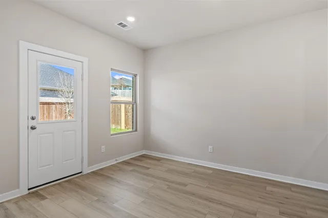 an empty room with wooden floor and windows