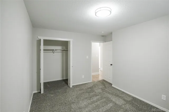 an empty room with closet and windows