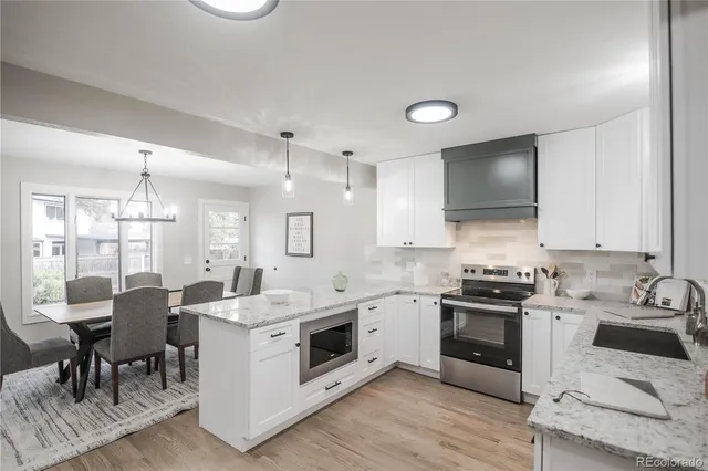 a kitchen that has a lot of white cabinets and stainless steel appliances