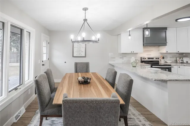 a kitchen with stainless steel appliances granite countertop a sink a stove a dining table and chairs