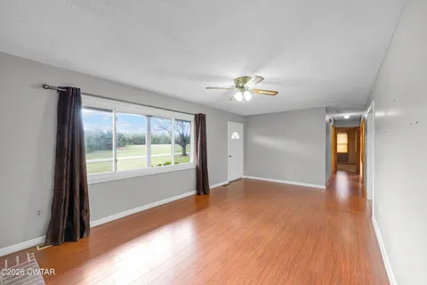 a view of an empty room with wooden floor and furniture