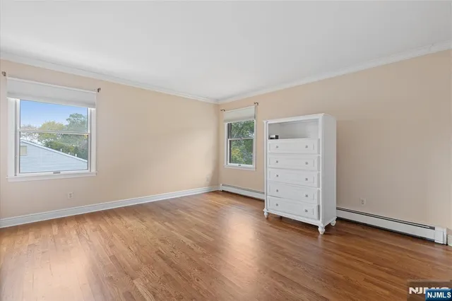 an empty room with wooden floor cabinet and windows