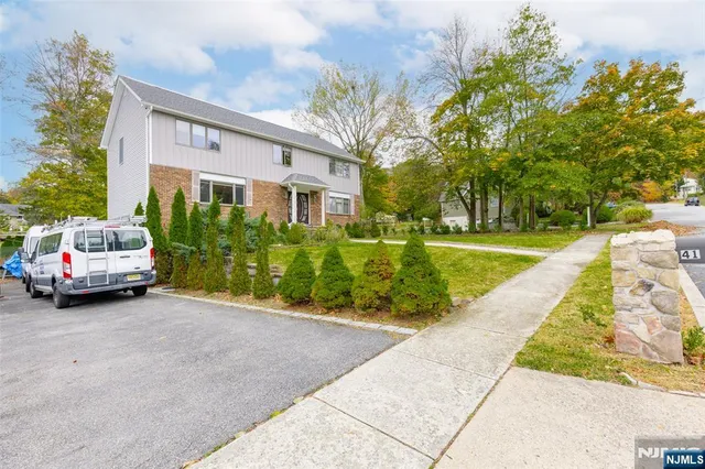 a view of a house with a cars park side of a road