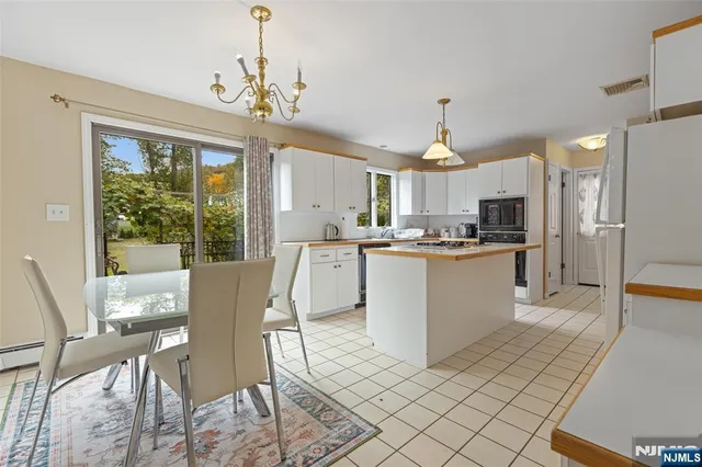 a living room with stainless steel appliances granite countertop furniture and a chandelier