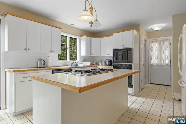 a kitchen with kitchen island granite countertop a sink appliances a counter top space cabinets and a window