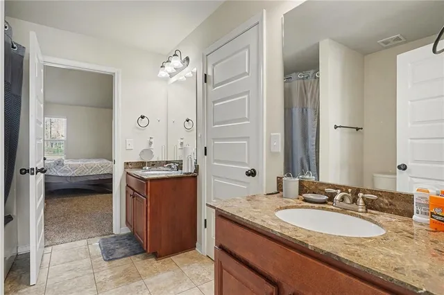 a en suite bathroom with a granite countertop sink and a mirror