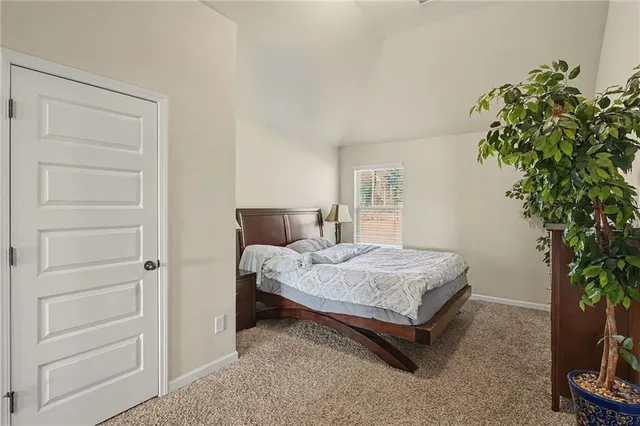 a bed sitting in a spacious bedroom next to a window and a potted plant