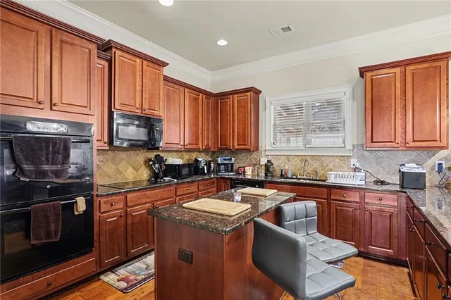 a kitchen with stainless steel appliances granite countertop a sink stove microwave and refrigerator