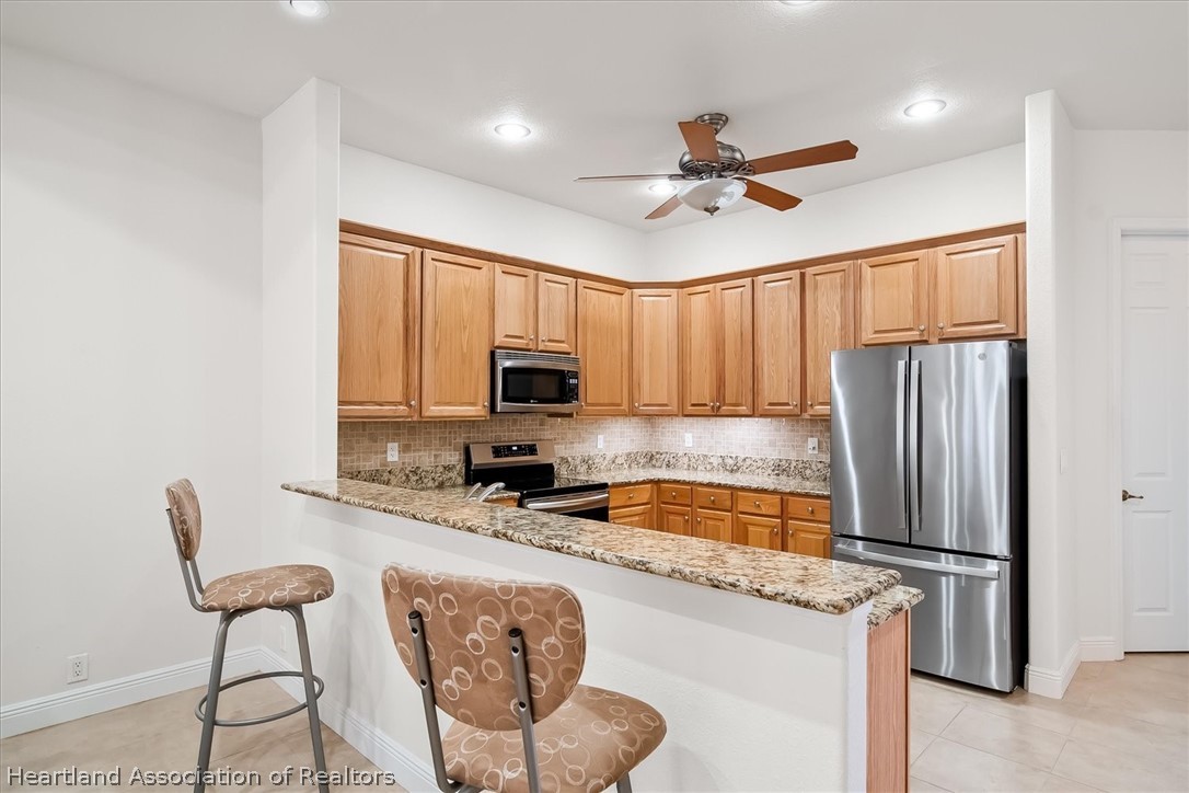 5224 Haw Branch Road Sebring, FL 33875 - Photo 7 of 40 a kitchen with stainless steel appliances granite countertop a refrigerator a sink a stove a dining table and chairs with wooden floor