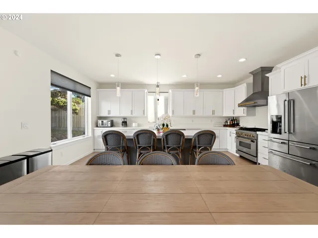 a large kitchen with kitchen island a stove a refrigerator a sink and white cabinets with wooden floor