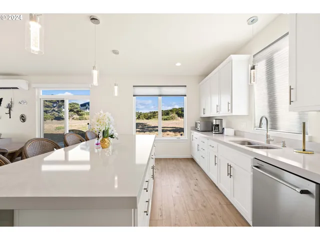 a large white kitchen with a large window a sink and white appliances