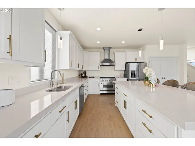 a large white kitchen with stainless steel appliances lots of counter space sink and cabinets