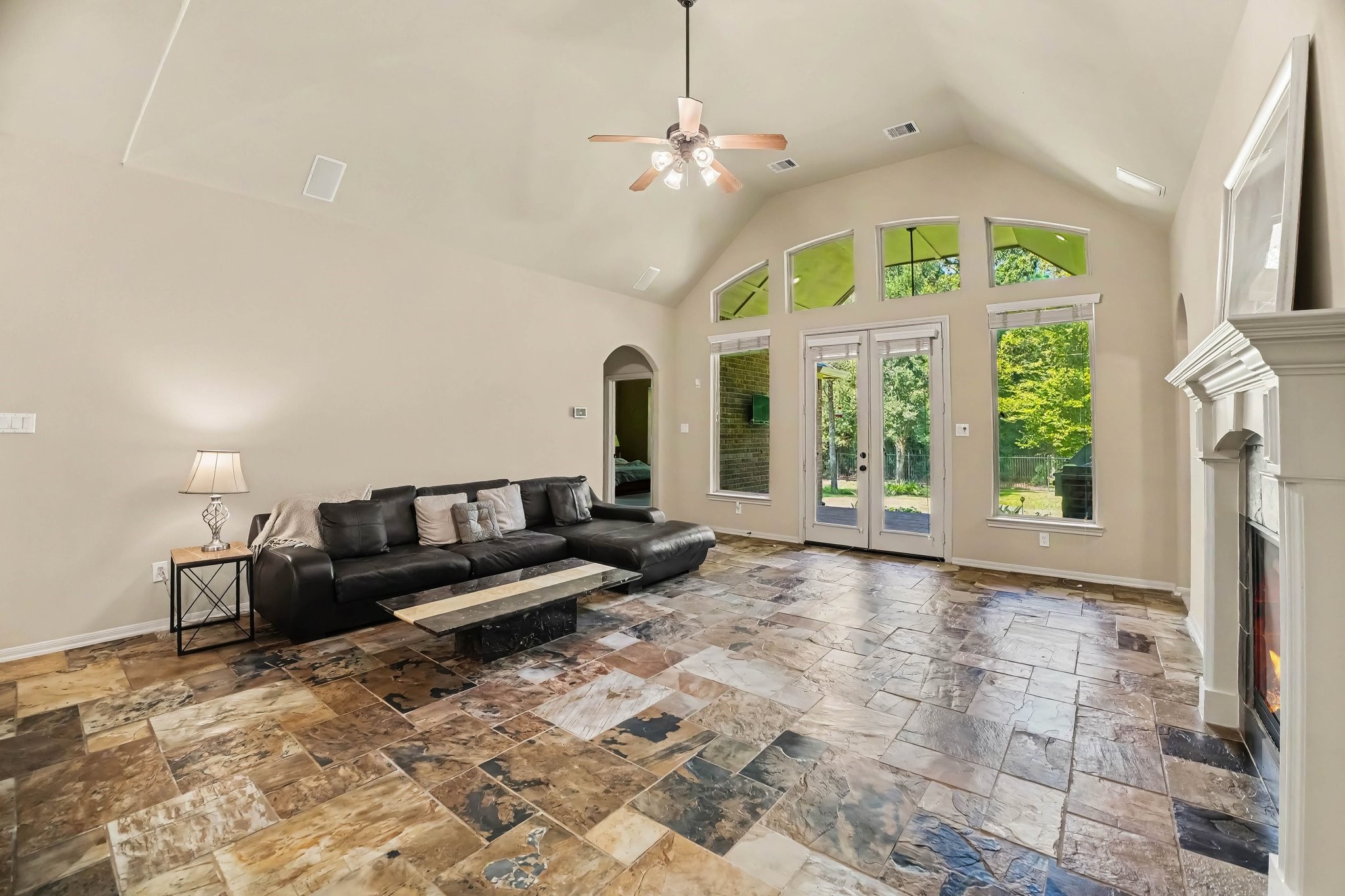62 Sandwell Place Spring, TX 77389 - Photo 10 of 50 Spacious living room with vaulted ceilings, elegant stone flooring, and large windows offering abundant natural light and serene views.