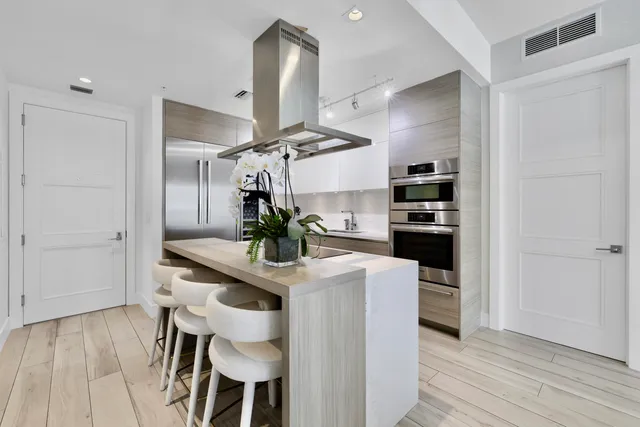 a kitchen with stainless steel appliances kitchen island a refrigerator and table chair