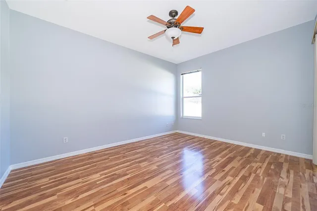 an empty room with a window and a ceiling fan