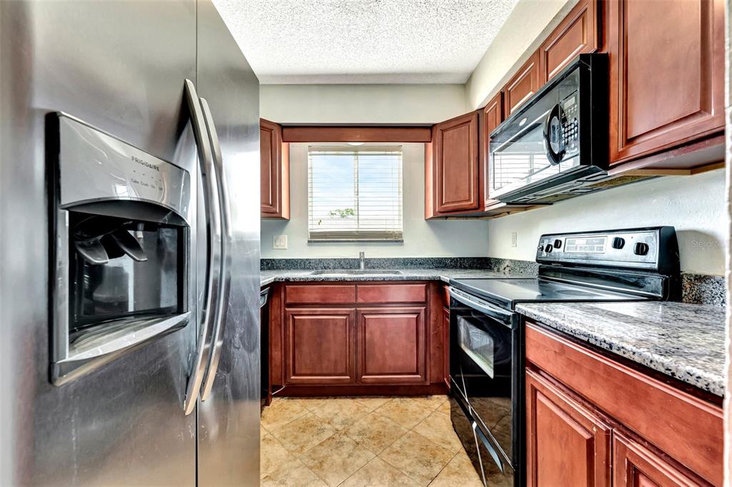 13300 Walsingham Road, Unit 56 Largo, FL 33774 - Photo 15 of 35 a kitchen with stainless steel appliances granite countertop a stove a sink and a microwave